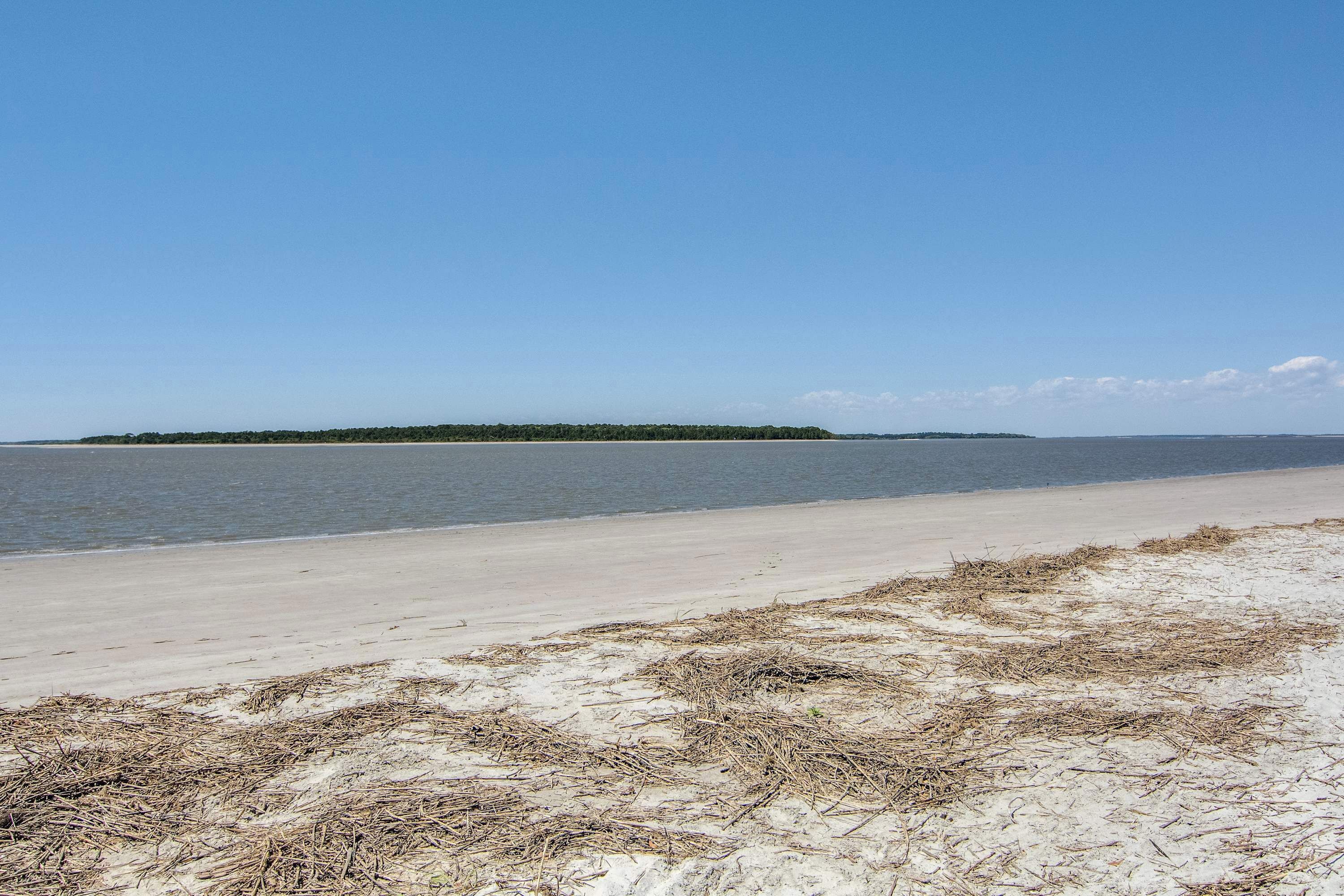 Ein Strand mit sandigem Ufer und einer kleinen Insel in der Ferne.
