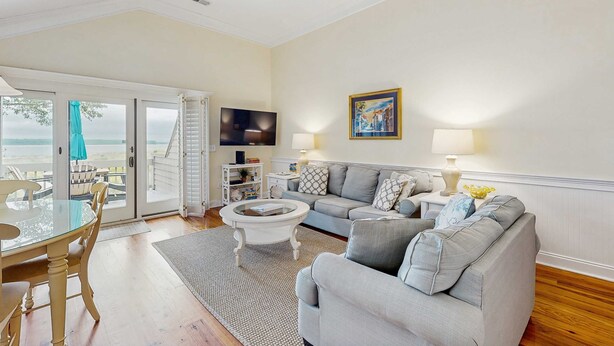 A living room with a sofa, coffee table, TV, and a view of the outdoors. - Condo with sunset views, with ocean/inlet views - walk to the Beach Club (Seabrook Island)