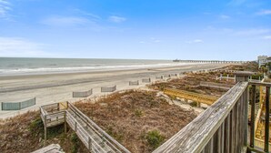 Een uitzicht op het strand met houten vlonders, een steiger en zand.