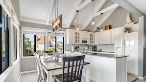 Una cocina moderna con armarios blancos, una mesa de comedor de madera y una isla grande.