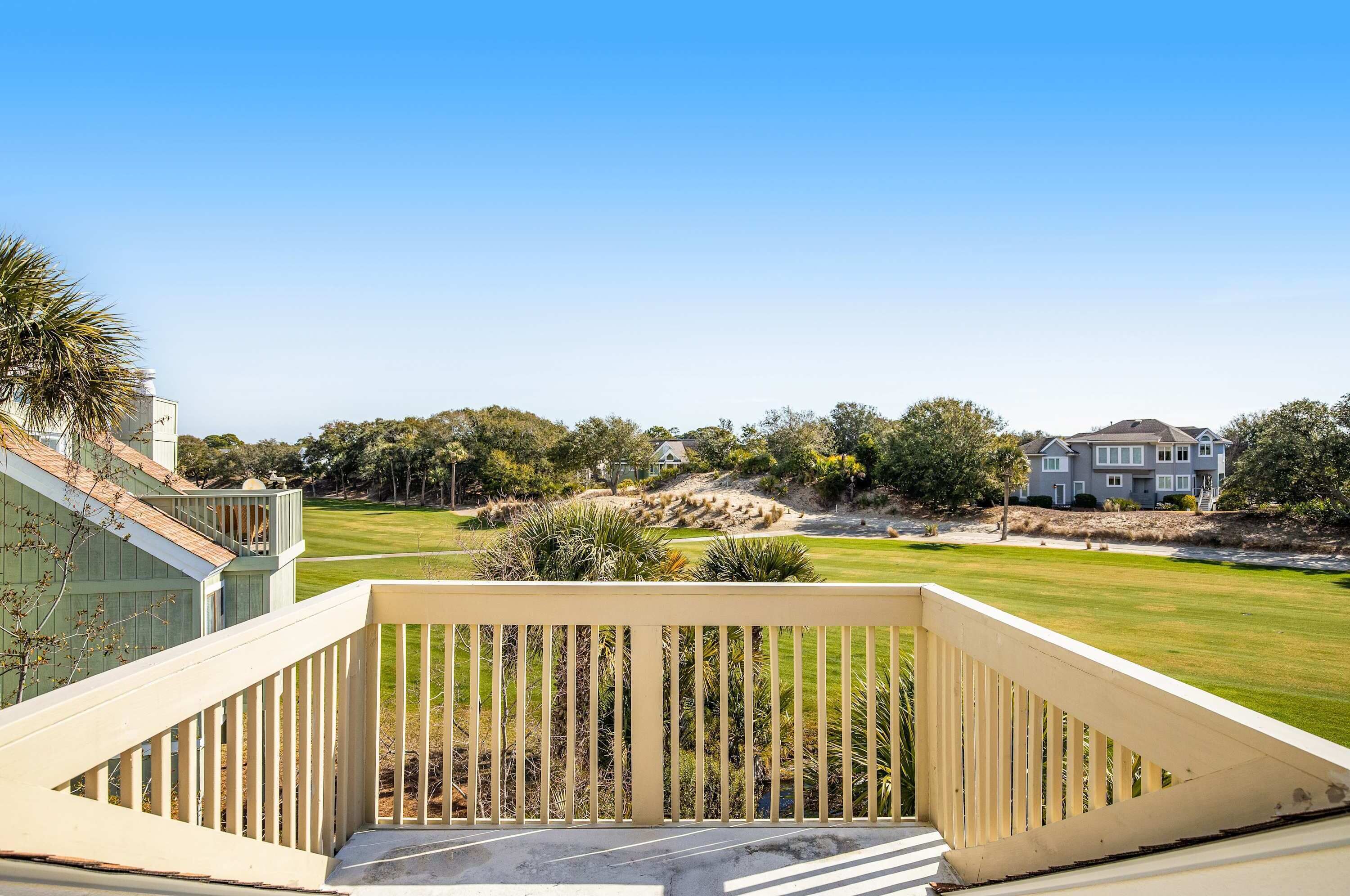A residential property with a deck, a well-maintained lawn, and a large house in the background.