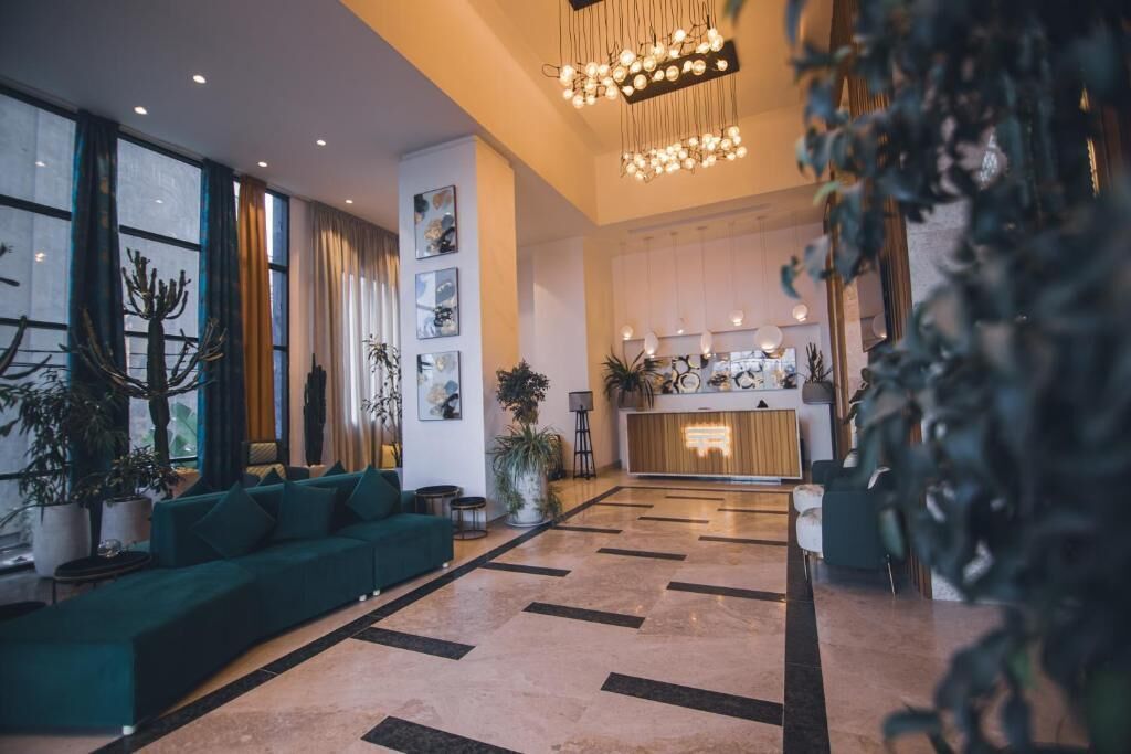 A spacious lobby with a green sofa, potted plants, and a reception desk.