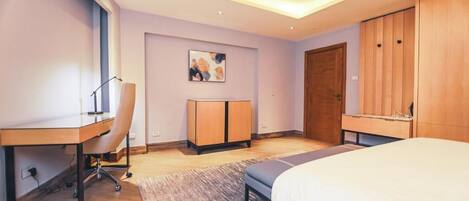 A modern bedroom with a desk, chair, bed, wardrobe, and a painting on the wall.