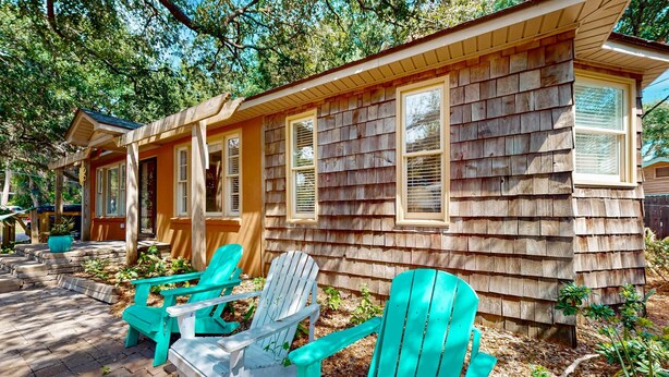 Une cabane en bois dotée d’une véranda, d’un espace salon extérieur et d’un jardin.
