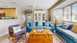 Un salon avec un canapé bleu, une table basse en bois et un fauteuil violet.