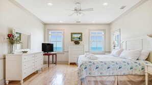 A bedroom with a bed, dresser, TV, and windows. - Gorgeous Beachfront Home w/ Oceanfront Views, Deck, Beach Boardwalk & WiFi (Folly Beach)