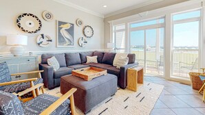 Ein modernes Wohnzimmer mit einem Ecksofa, einem Couchtisch und Blick ins Freie durch große Fenster.