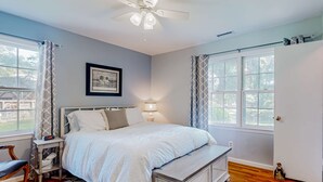 Une chambre à coucher avec un lit, une table de chevet, une lampe et un ventilateur de plafond.