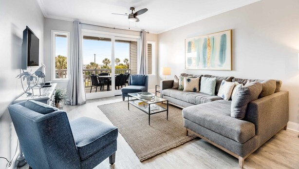Una sala de estar moderna con un sofá gris, un sillón azul y una mesa de centro de vidrio.