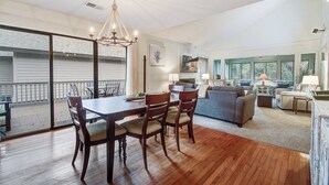 A spacious living area with a dining table, chairs, a sofa, and a balcony with a view. - Kiawah Resort snowbird hideaway with AC, steps to beach, near golf & tennis (Kiawah Island)