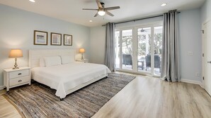 A bedroom with a bed, nightstands, a ceiling fan, and a view through a glass door. - Gorgeous home with private pool, deck, enclosed patio, central AC, & balcony (Isle of Palms)
