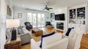A spacious living room with a fireplace, comfortable seating, and a television. - Gorgeous home with private pool, deck, enclosed patio, central AC, & balcony (Isle of Palms)