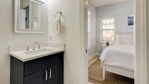 A bathroom with a white sink, black cabinets, and a mirror. - Gorgeous home with private pool, deck, enclosed patio, central AC, & balcony (Isle of Palms)