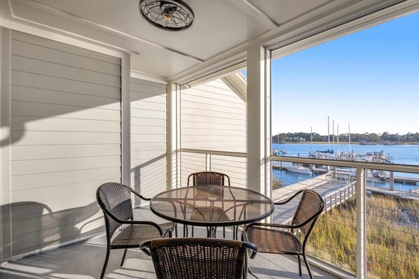 A balcony with a table and chairs, overlooking a marina with boats and a dock.