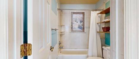 A bathroom with a bathtub, toilet, and a shower curtain.