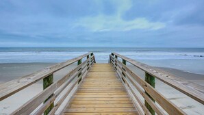 A wooden boardwalk leading to the beach with a cloudy sky. - Beach Across the Street Ocean View Home w/ Roof Deck, Porch, AC - Dogs OK (Folly Beach)