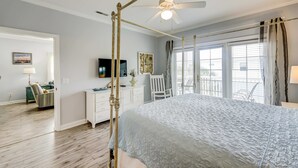 A bedroom with a four-poster bed, a ceiling fan, a desk with a chair, and a window with curtains. - Fantastic condo with water-view, pool, balcony, central AC, & washer/dryer (Folly Beach)