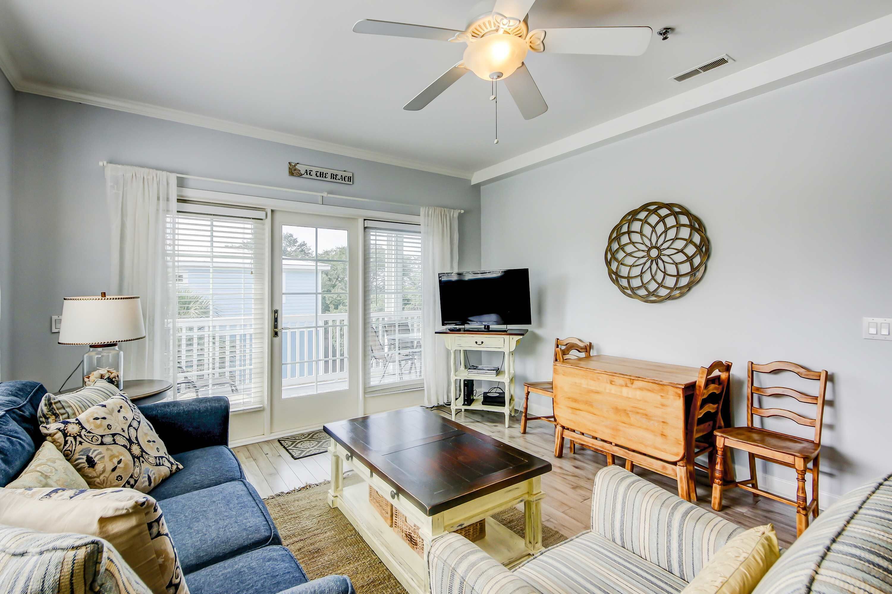 A living room with a sofa, a coffee table, a TV, and a dining area with chairs and a table.