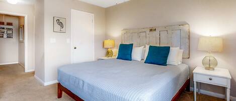 A bedroom with a bed, a ceiling fan, a nightstand, and a door.