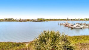 A marina with boats docked, a clear sky, and a grassy foreground. - Newly renovated two-story waterfront condo with screened porch, pool, & tennis (Folly Beach)