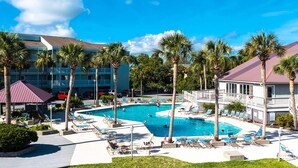 A hotel with a large pool surrounded by palm trees and lounge chairs. - Newly renovated two-story waterfront condo with screened porch, pool, & tennis (Folly Beach)