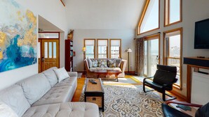 A spacious living room with a sofa, a coffee table, and a chair. There are large windows and a view of the outside. - Oceanfront home with stunning ocean views, central AC, and private W/D (Folly Beach)