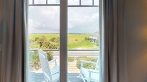 A view from a balcony with two white chairs, overlooking a green landscape and a building. - Oceanfront home with stunning ocean views, central AC, and private W/D (Folly Beach)