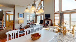 A spacious living area with a dining table, chairs, and a large window overlooking the sea. - Oceanfront home with stunning ocean views, central AC, and private W/D (Folly Beach)