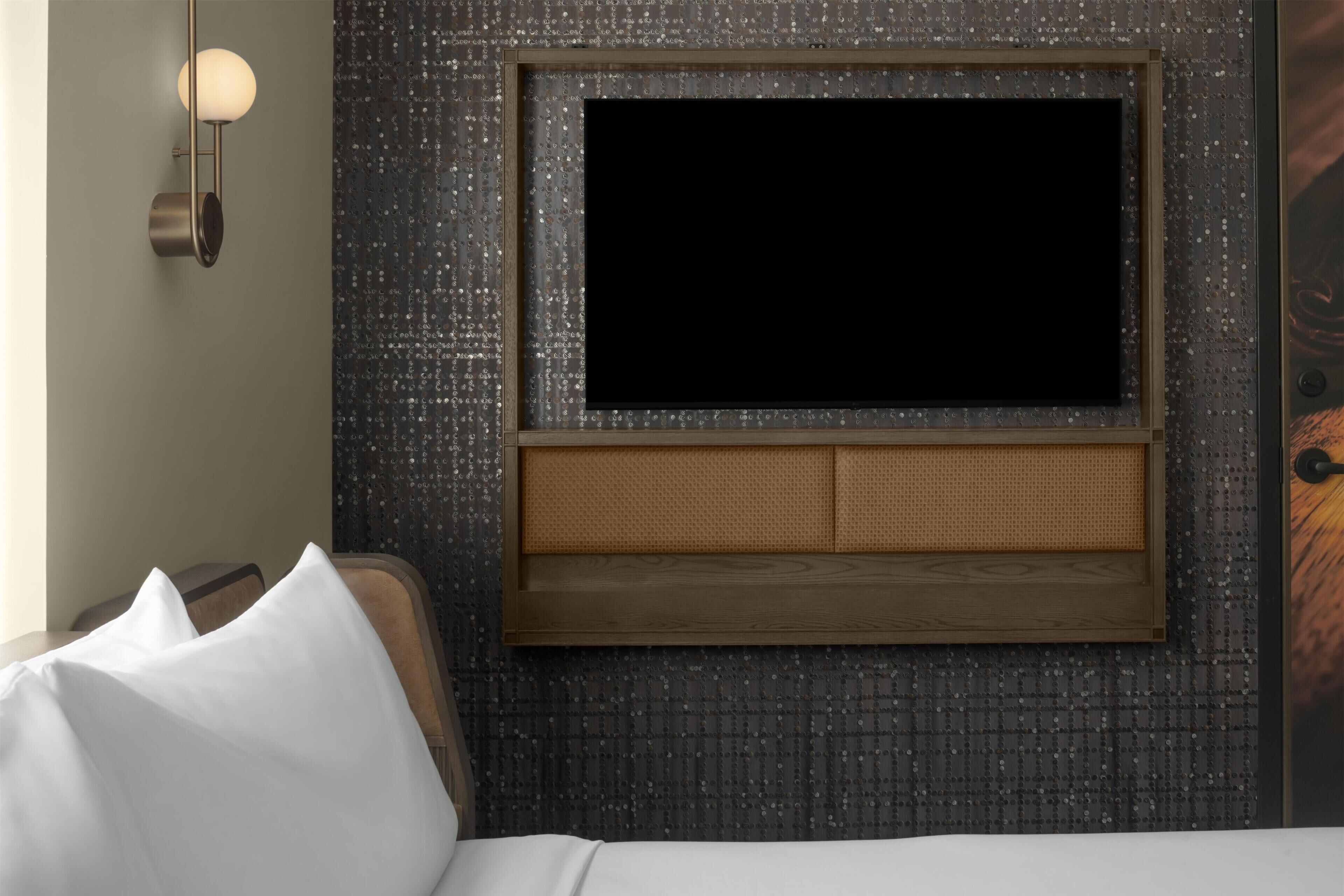 Ein Hotelzimmer mit einem Bett, einem an der Wand befestigten Fernseher und einer Wand mit Struktur.