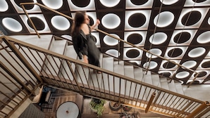 A modern interior with a staircase, wooden railings, and a ceiling with circular light fixtures. - Motto by Hilton Nashville Downtown (Nashville)