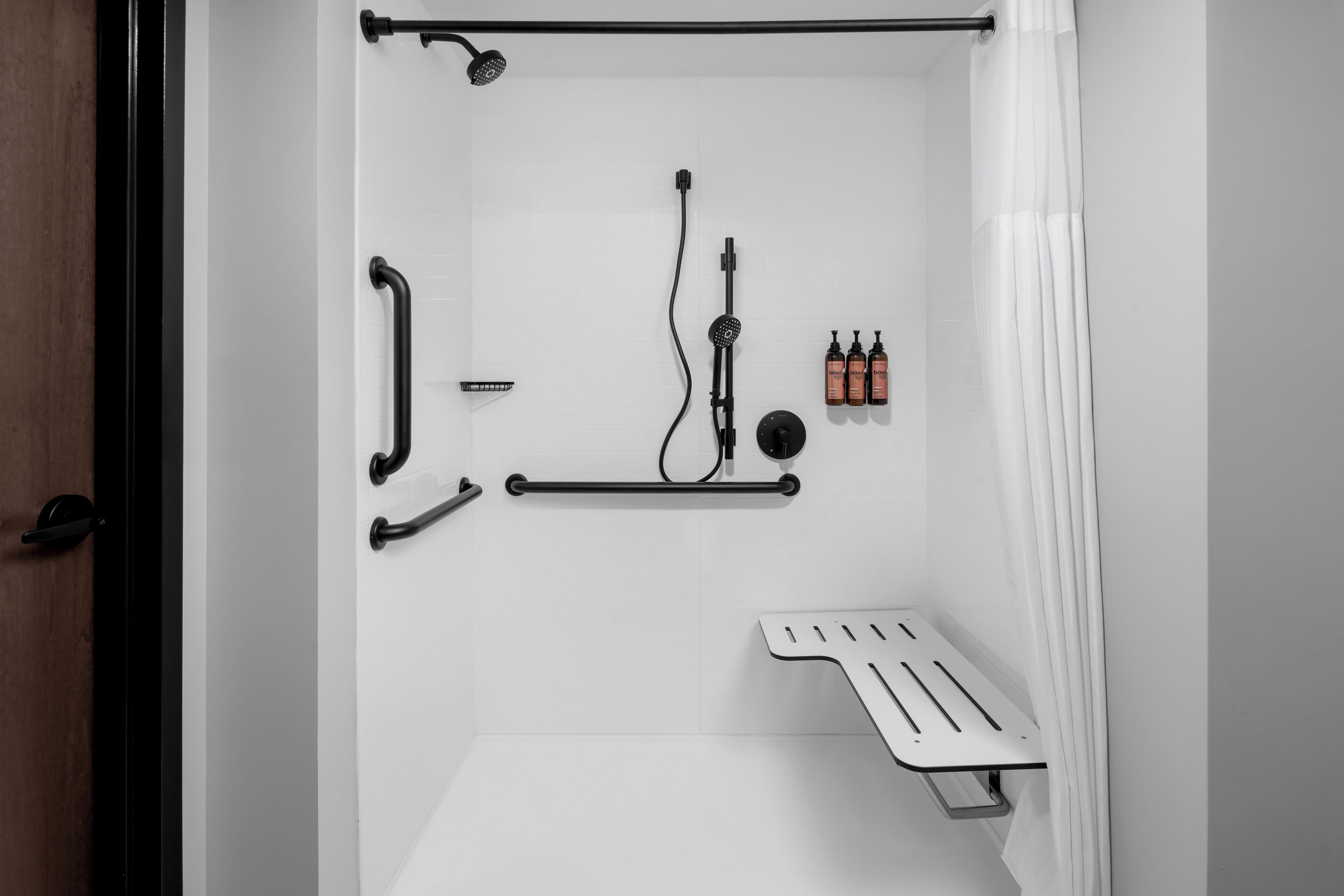 Une douche moderne dotée d’un pommeau de douche à main, d’un flexible de douche, d’un dispositif de commande de douche à main et d’un receveur de douche.