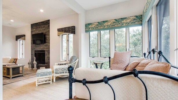 A modern living room with a fireplace, comfortable seating, and large windows offering a view of the outdoors.