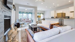 A spacious living room with a fireplace, a dining area, and a kitchen.