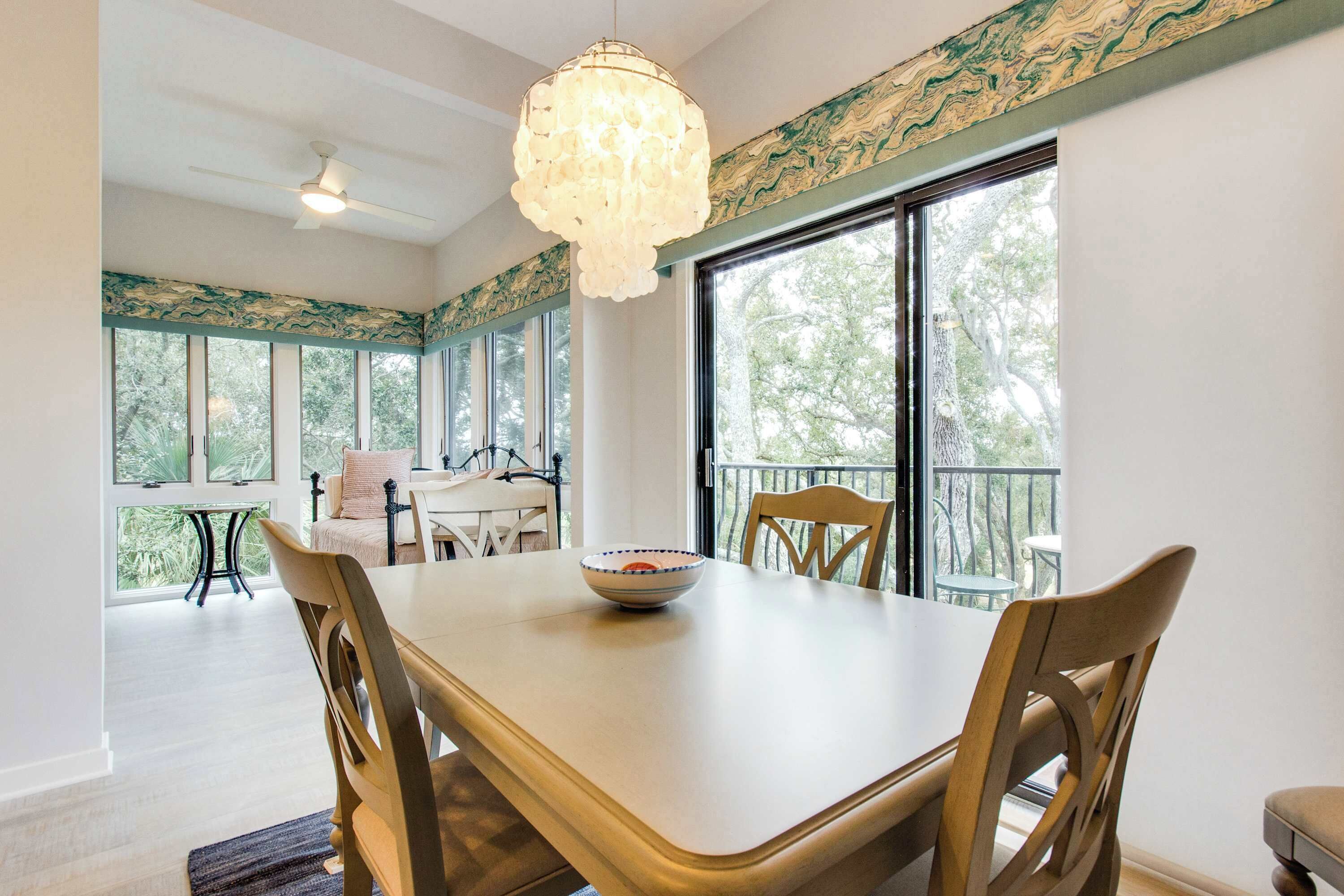 A dining area with a large table, chairs, a bowl, and a chandelier.