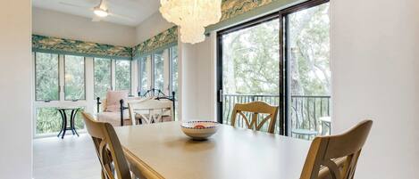 A dining area with a large table, chairs, a bowl, and a chandelier.