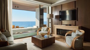 Ein modernes Wohnzimmer mit großem Fernseher, bequemen Sitzmöglichkeiten, einem Kamin und Meerblick.