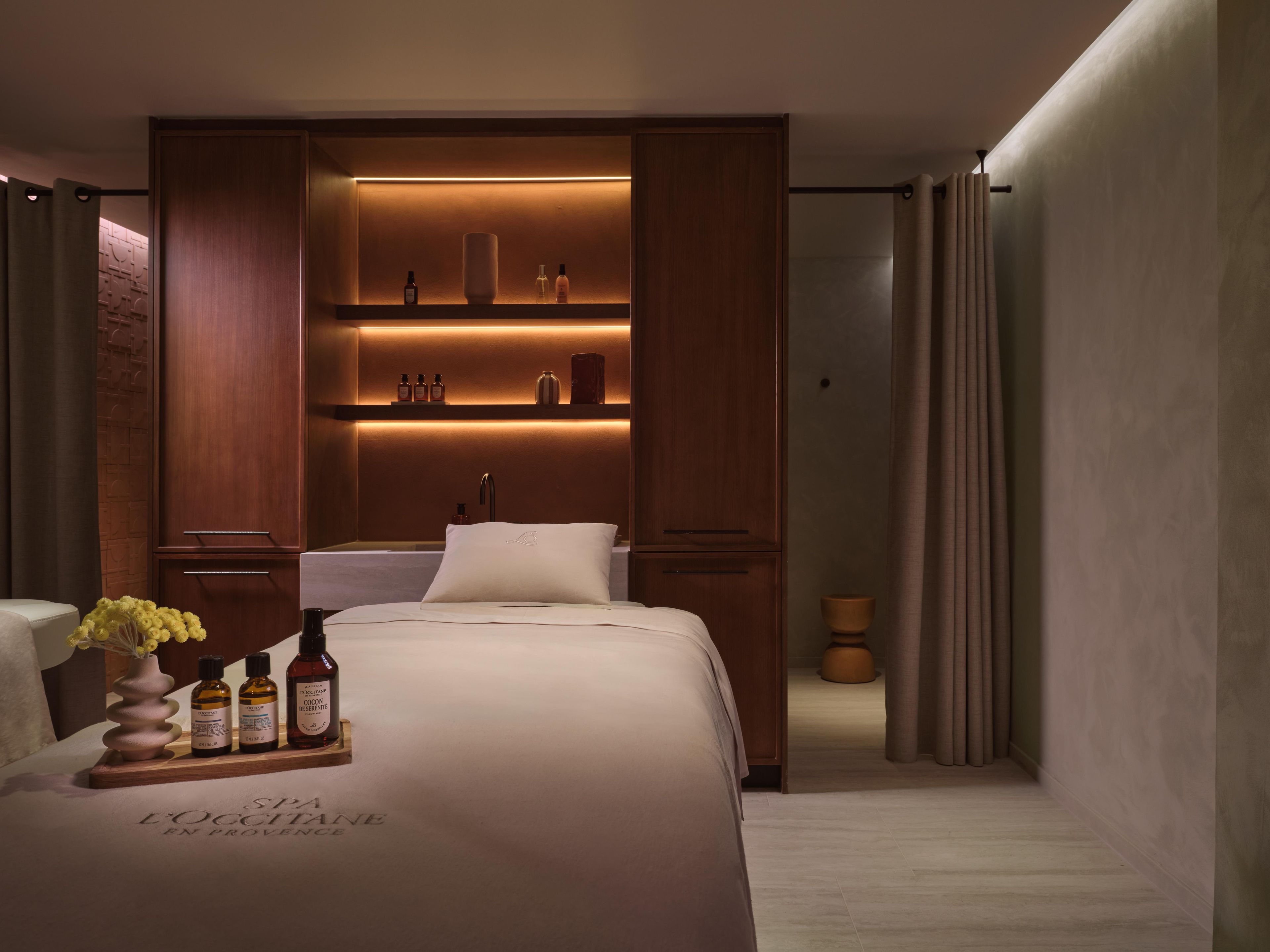 Une chambre d’hôtel comprenant un lit, une coiffeuse avec un miroir et une étagère avec des articles de toilette.
