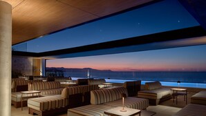 Eine moderne Lounge mit Sofas und Tischen, ein großes Fenster mit Meerblick und Blick auf den Horizont.