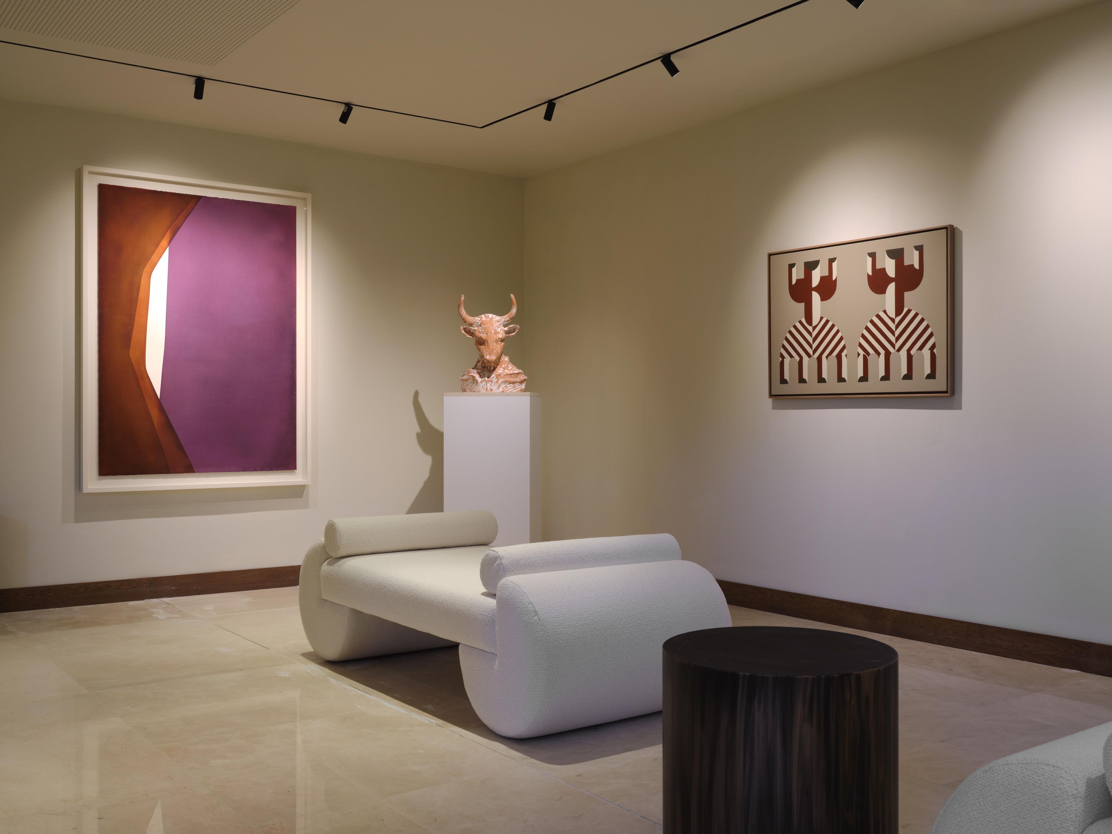 Ein modernes Zimmer mit einem großen abstrakten Gemälde, einer Skulptur und einem geometrischen Kunstwerk an der Wand.