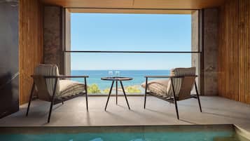 Habitación moderna con un ventanal grande, dos sillas, una mesita y una piscina.