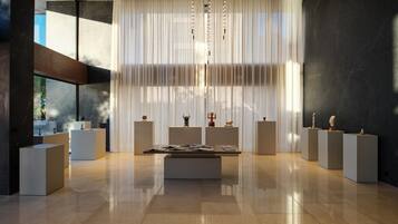 A modern interior with a central display table, white curtains, and marble flooring.