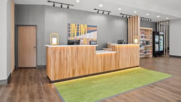 A hotel reception desk with a modern design, a green carpet, and a wall-mounted artwork.