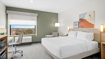 Una habitación de hotel con cama, escritorio, silla y vista a la ciudad.