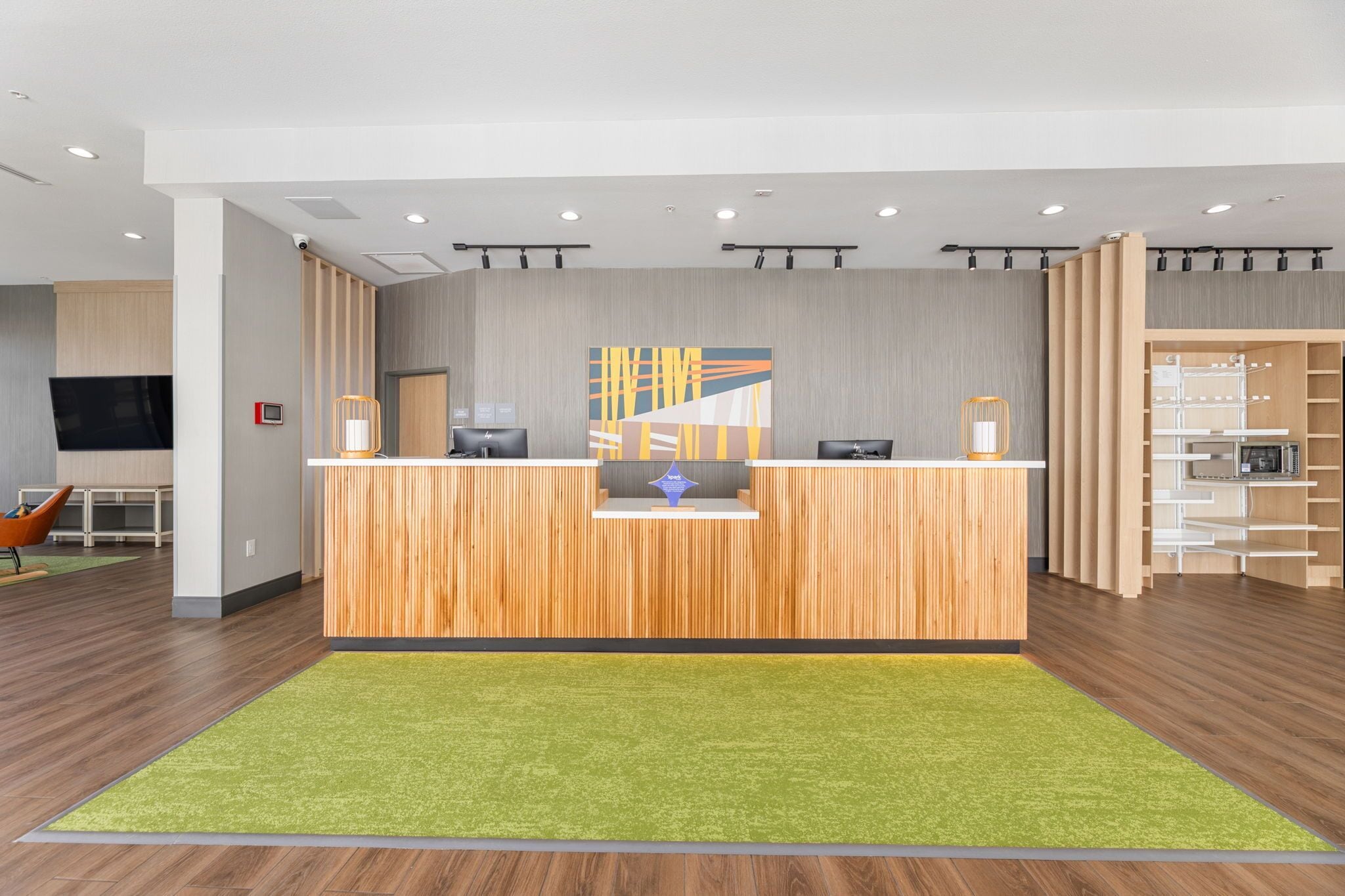 Un'area reception con un bancone in legno, una moquette verde e un arredamento moderno.