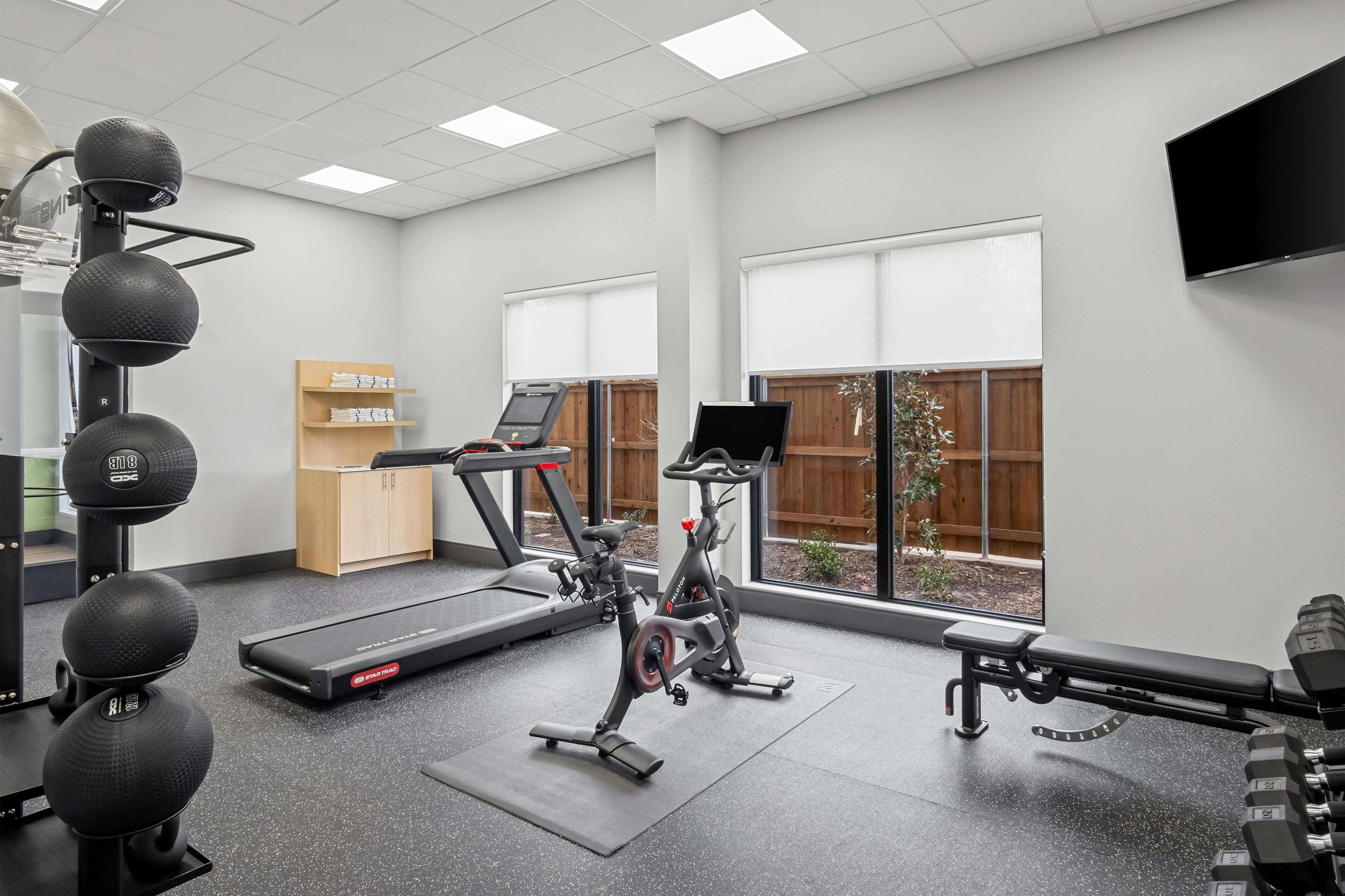 Une salle de sport équipée de machines de cardio, d’haltères et d’un tapis de course.