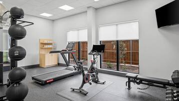 Une salle de sport équipée de machines de cardio, d’haltères et d’un tapis de course.