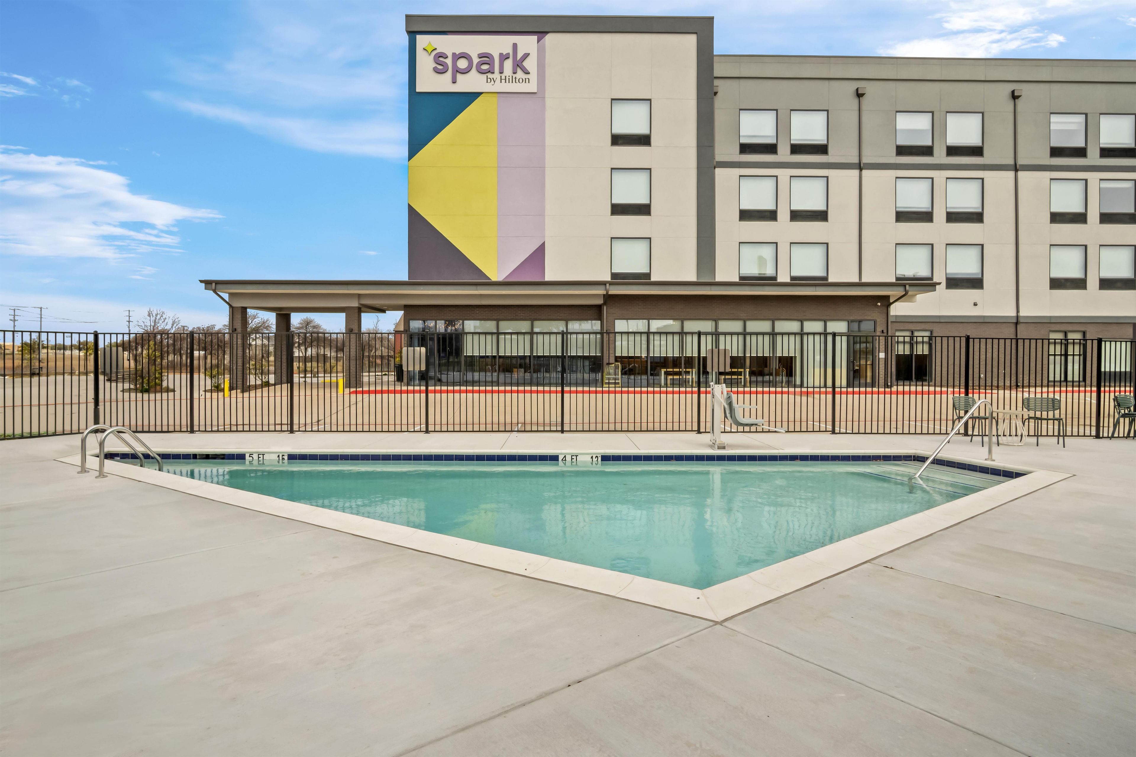 A hotel with a pool area, a covered seating area, and a sign indicating it's a Hilton property.