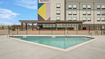 A hotel with a pool area, a covered seating area, and a sign indicating it's a Hilton property.