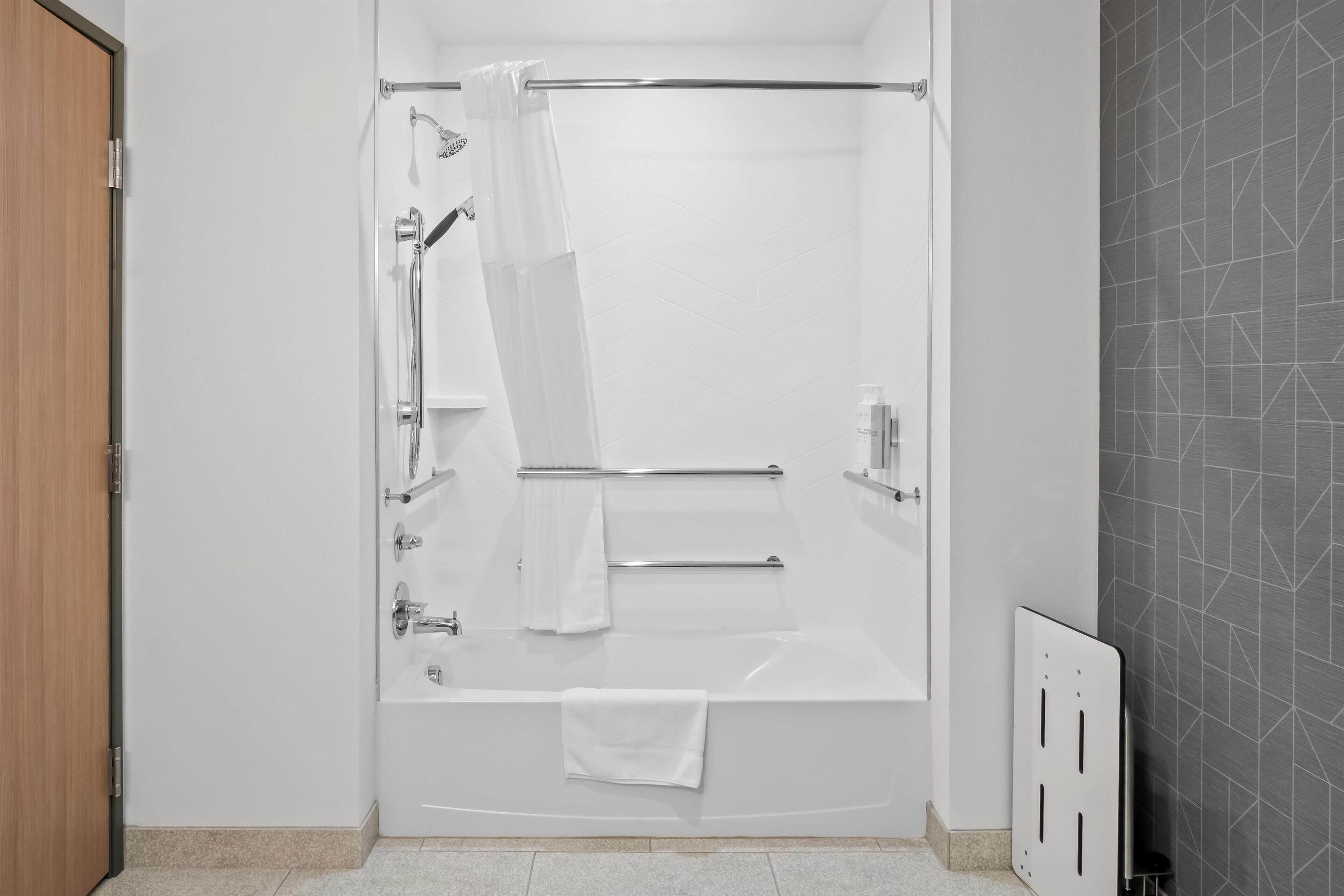 A modern bathroom with a bathtub, shower, and towel rack.