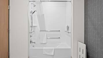 A modern bathroom with a bathtub, shower, and towel rack.